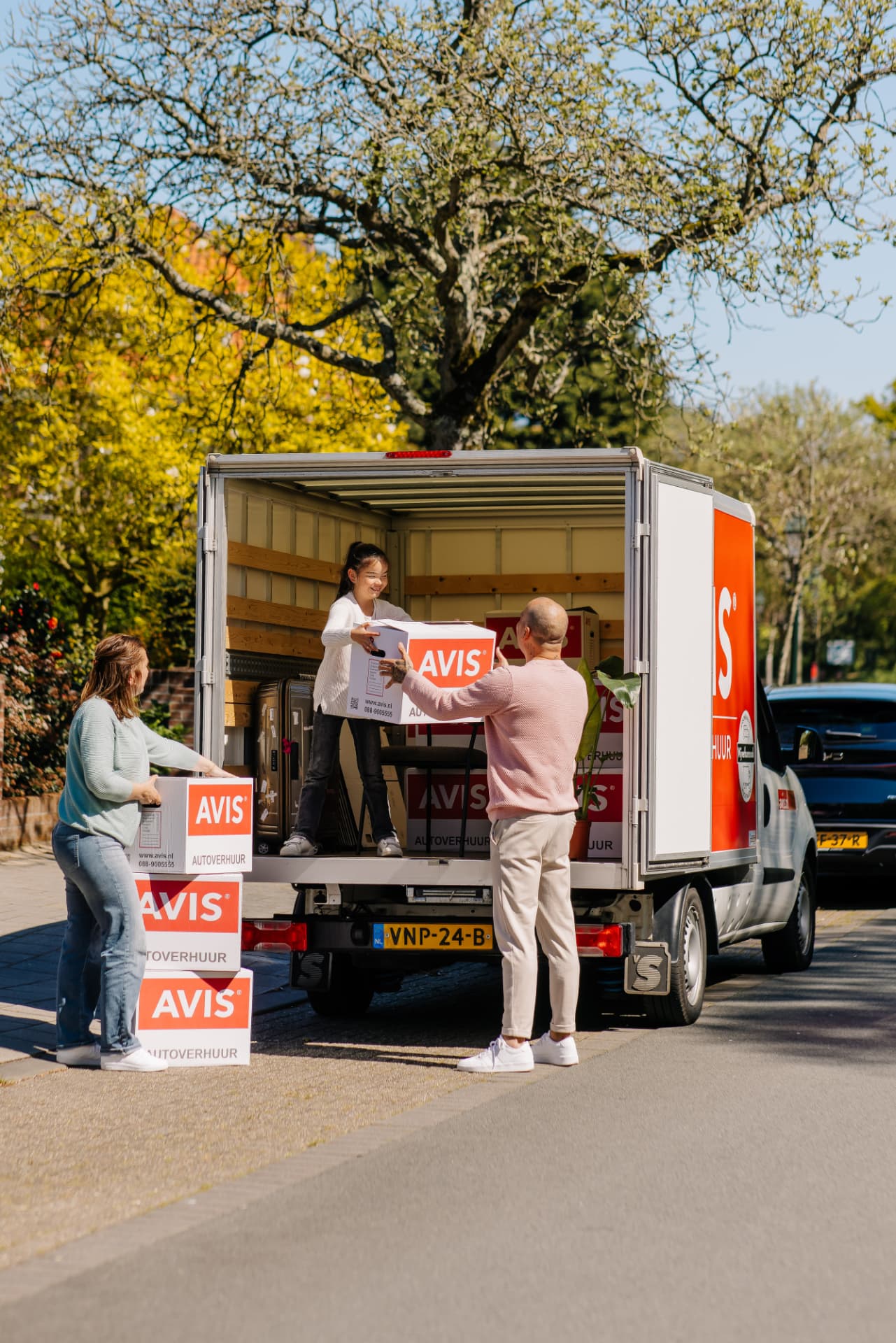 Gezin laadt dozen in de Avis-verhuiswagen